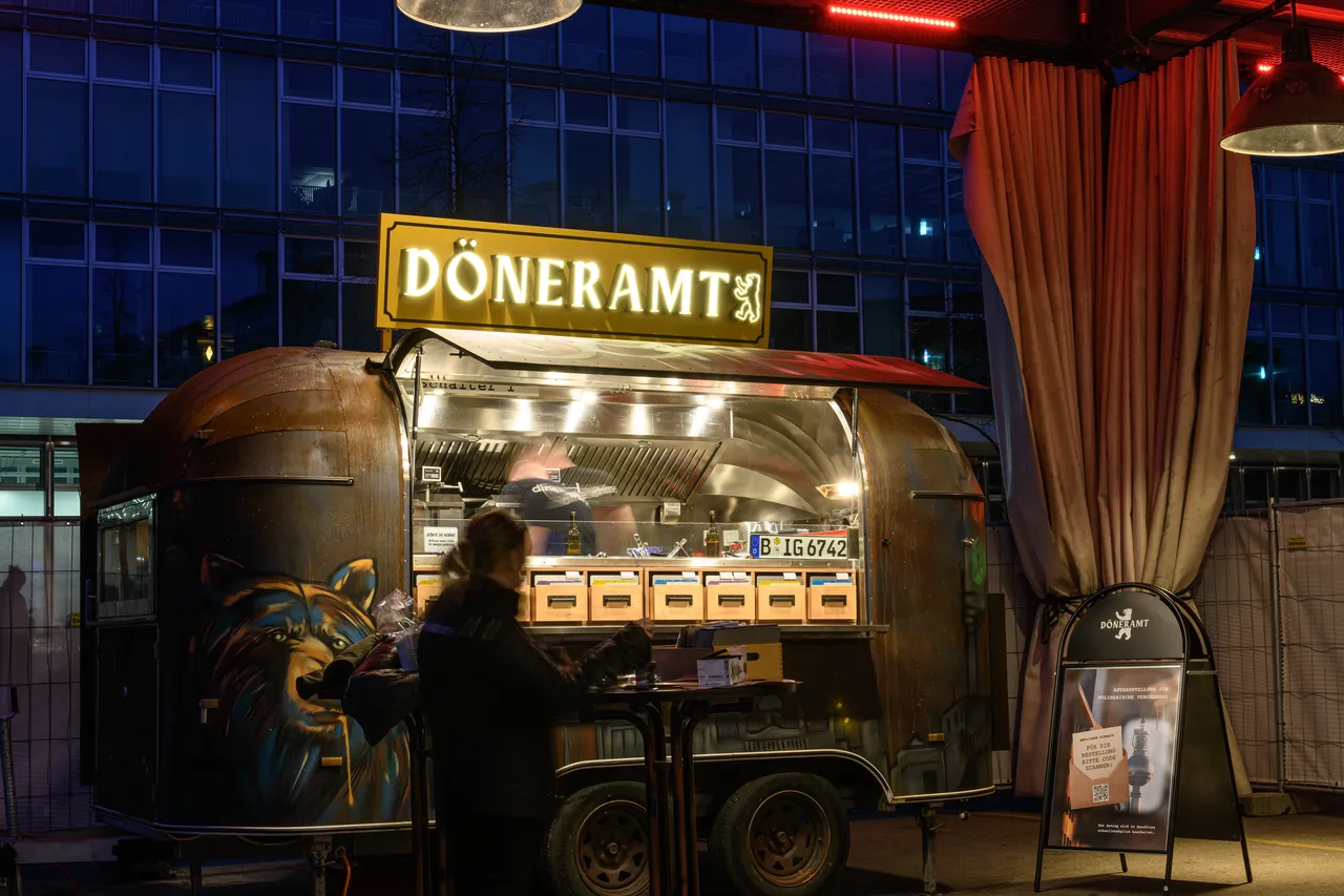 Der Döneramt Streetfood-Foodtruck in der Dämmerung, mit Bär-Graffiti an der Seite und DÖNERAMT-Leuchtschrift
